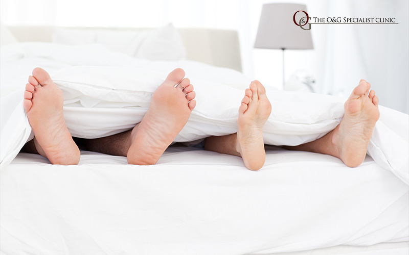 Couple's feet under duvet in bed.