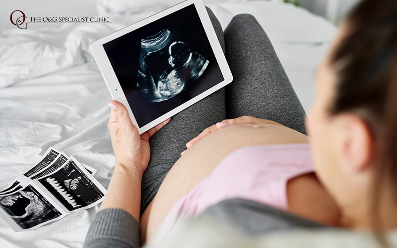 Pregnant woman viewing baby's ultrasound on tablet.