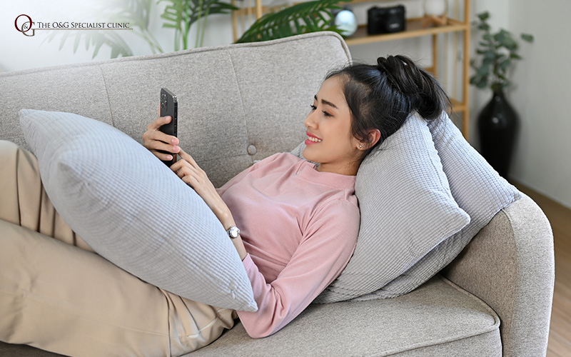 Woman relaxing, relieved from bloating symptoms at O&G Clinic.